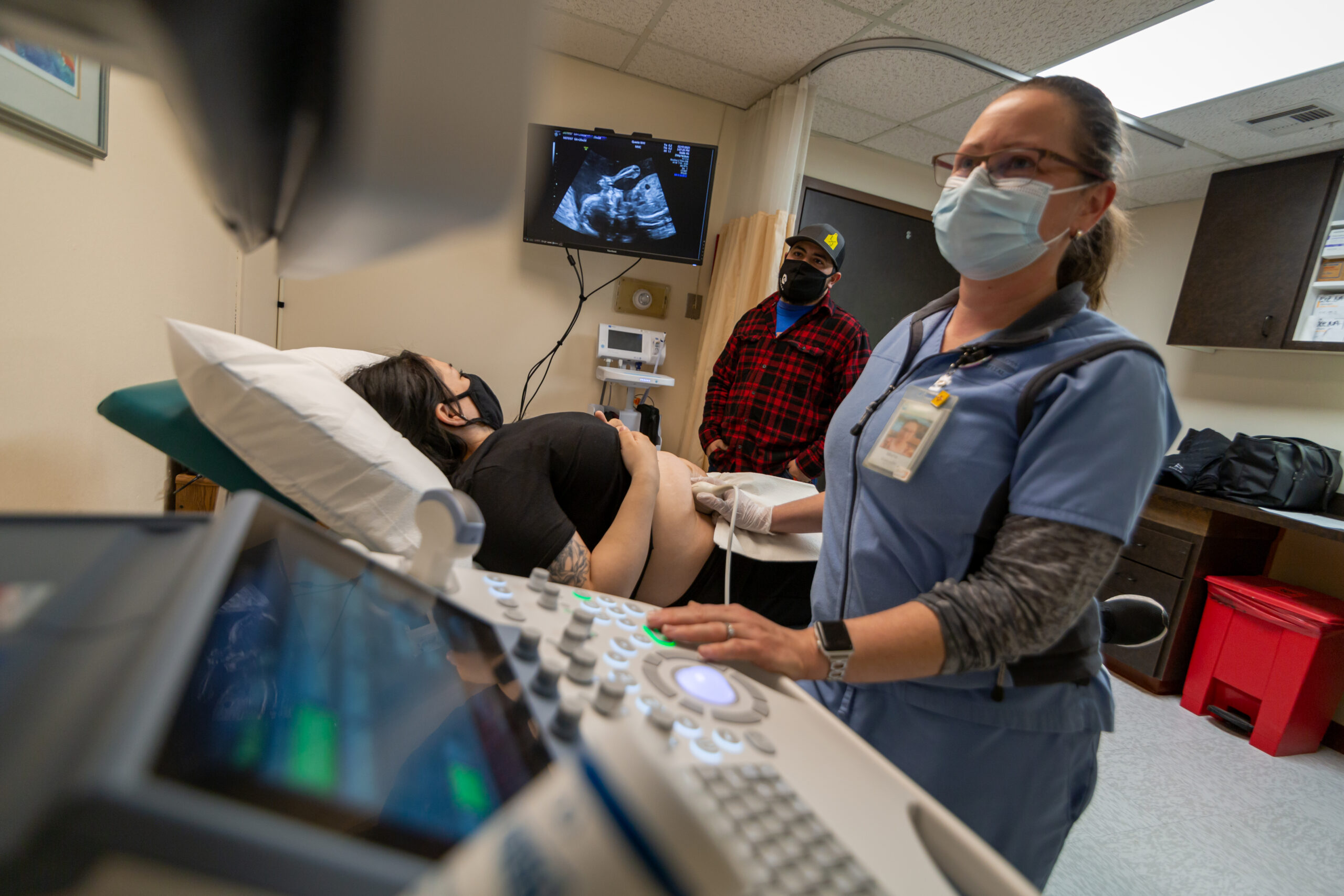 A healthcare professional conducts an ultrasound for a pregnant woman in a medical examination room.