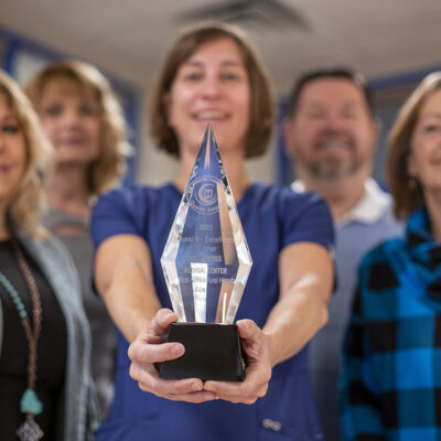 Holy Cross Medical Center team celebrates receiving the 2021 Quest for Excellence Quality Award with a trophy.