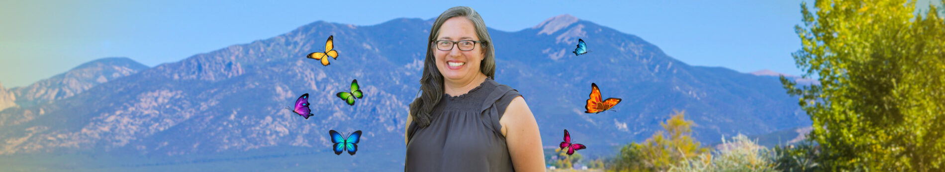 A smiling woman stands against a scenic mountain backdrop, surrounded by colorful butterflies, promoting community engagement with kids.
