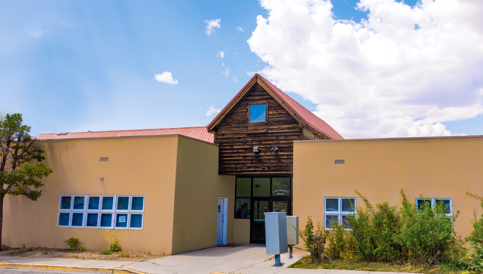 Holy Cross Cardiology building in Taos features a blend of modern and rustic architecture under a blue sky.